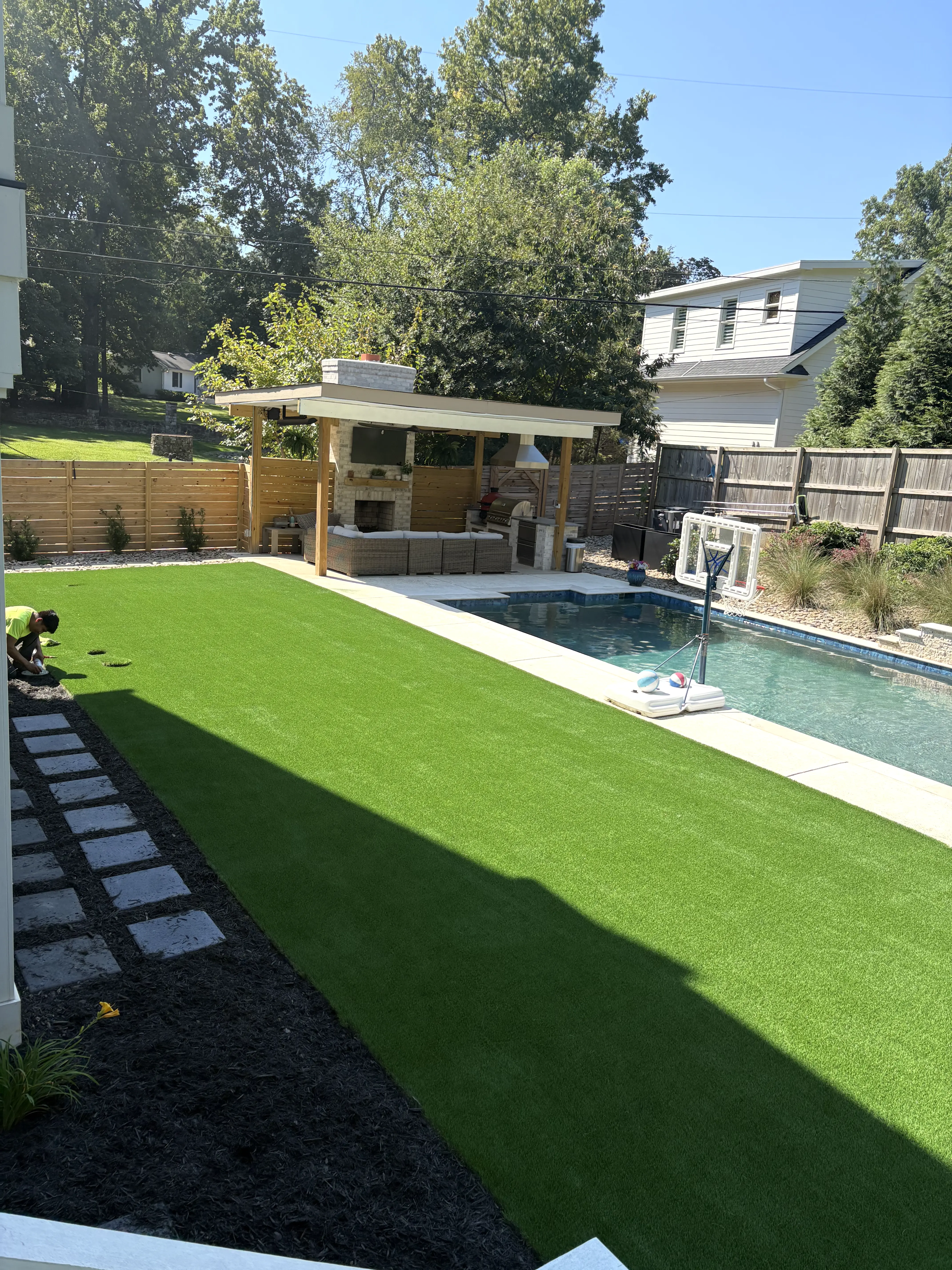Beautiful residential backyard with professionally installed artificial turf beside a pool in Charlotte NC - family-friendly lawn