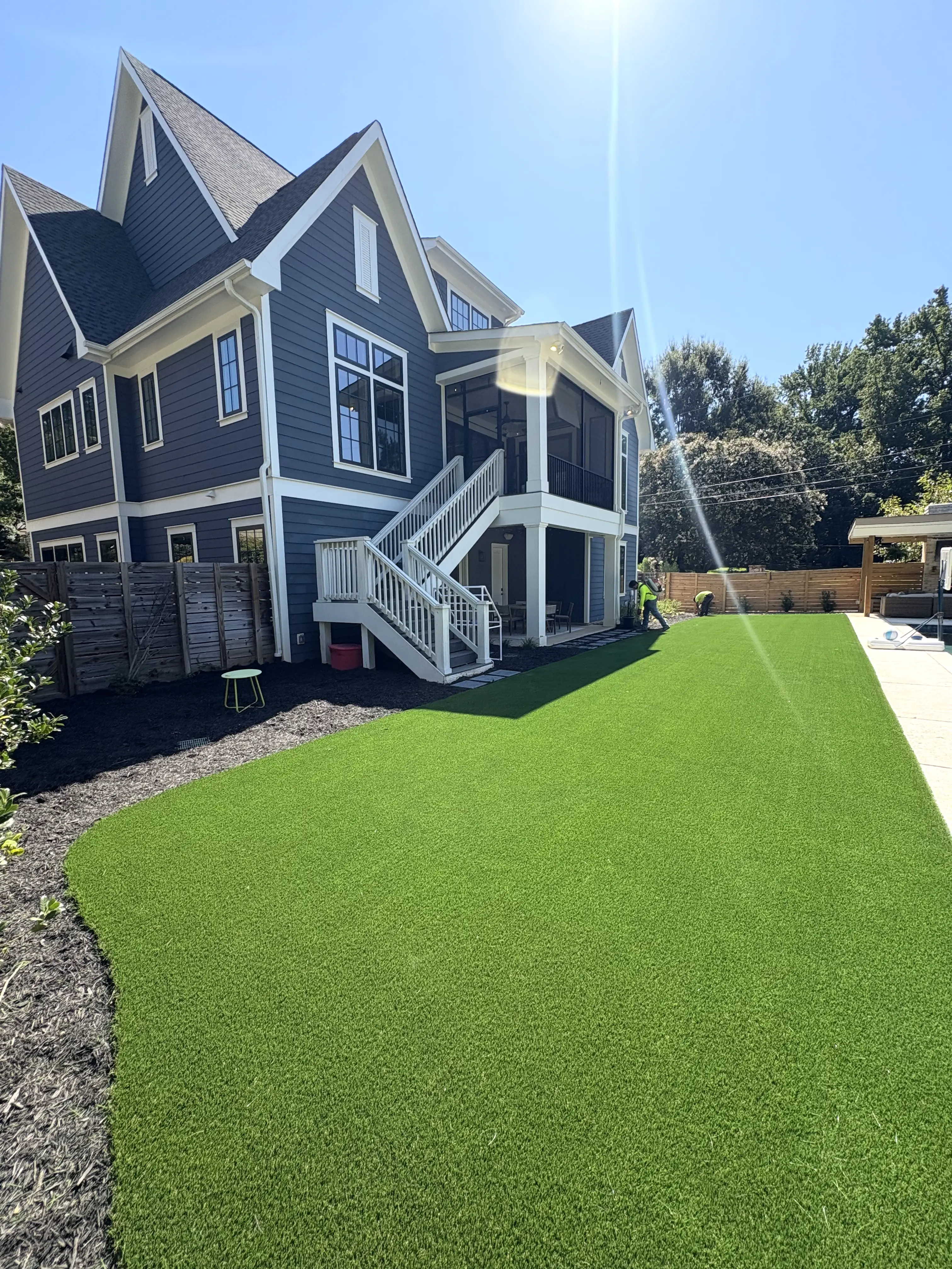 Expansive freshly installed artificial turf backyard at a modern blue craftsman home in Charlotte NC