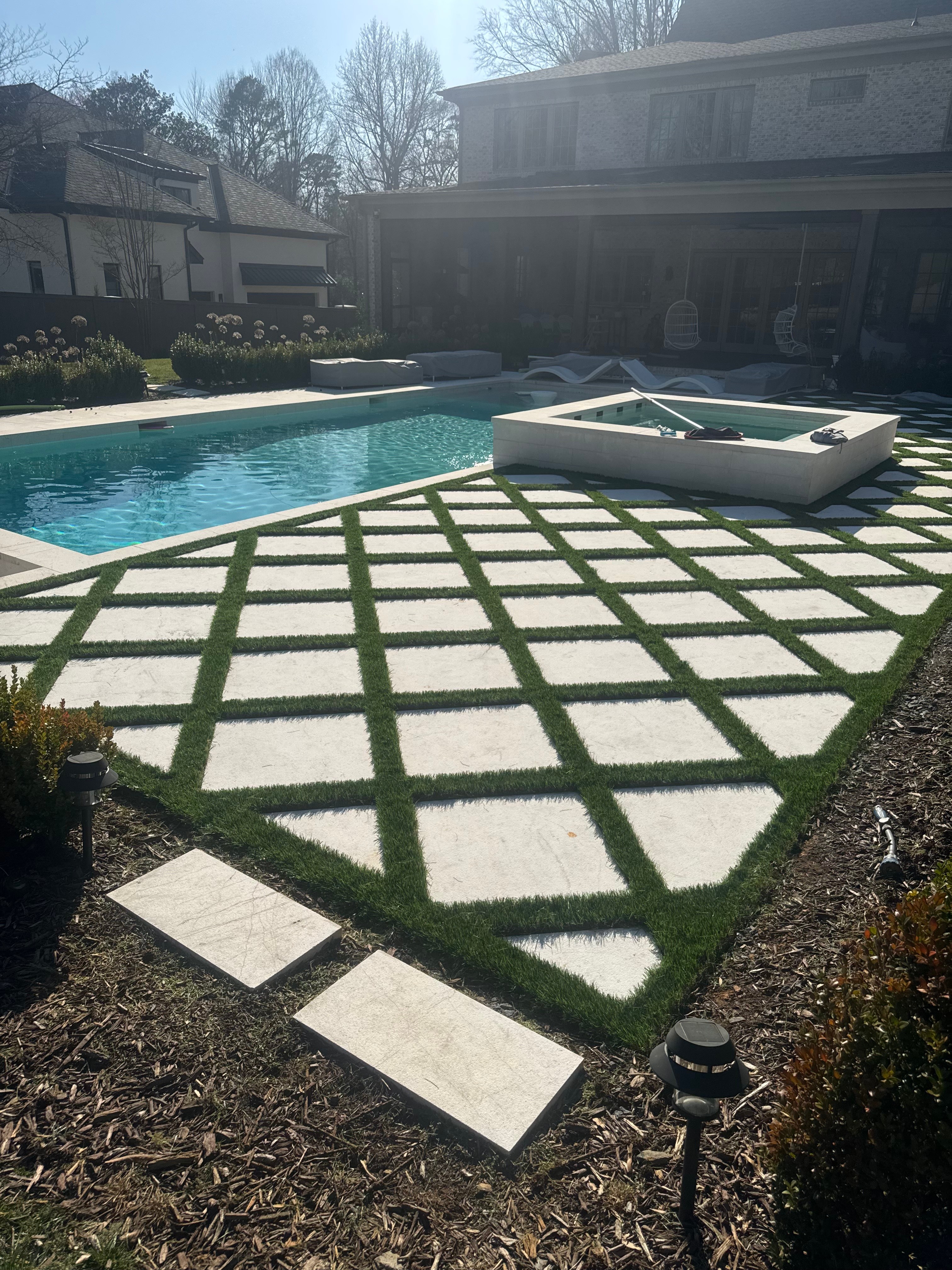 Modern poolside patio with checkerboard pattern of synthetic turf and pavers - Charlotte NC project