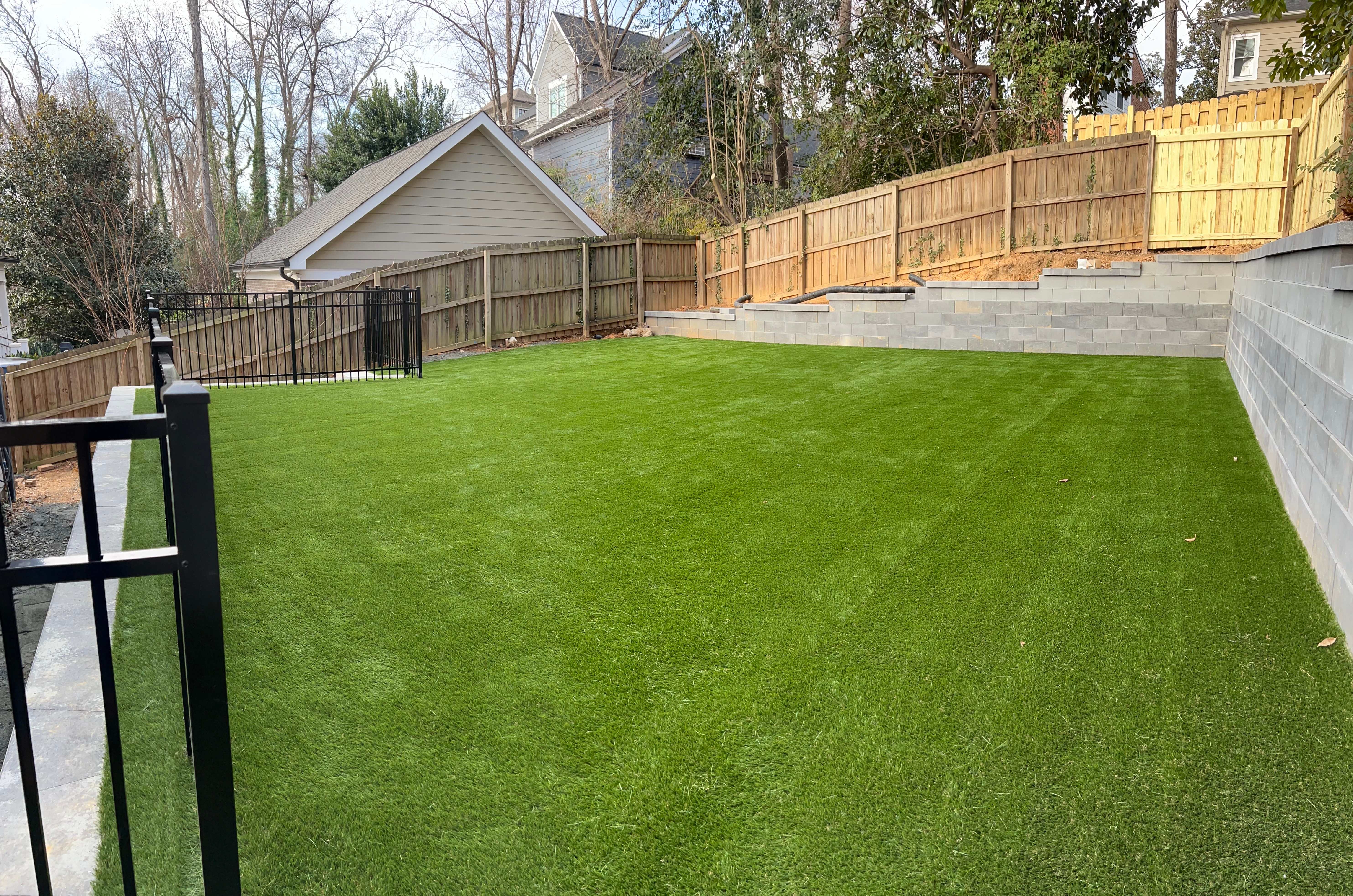 Clean, terraced backyard with privacy fence and artificial turf installation in Charlotte NC